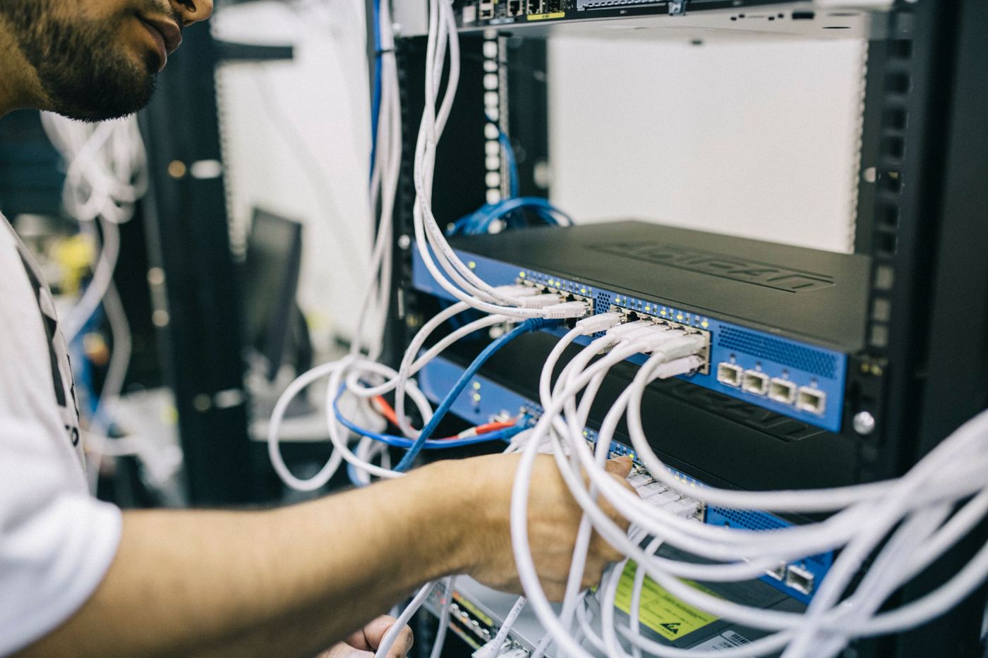 Technician connecting network cables in a server rack